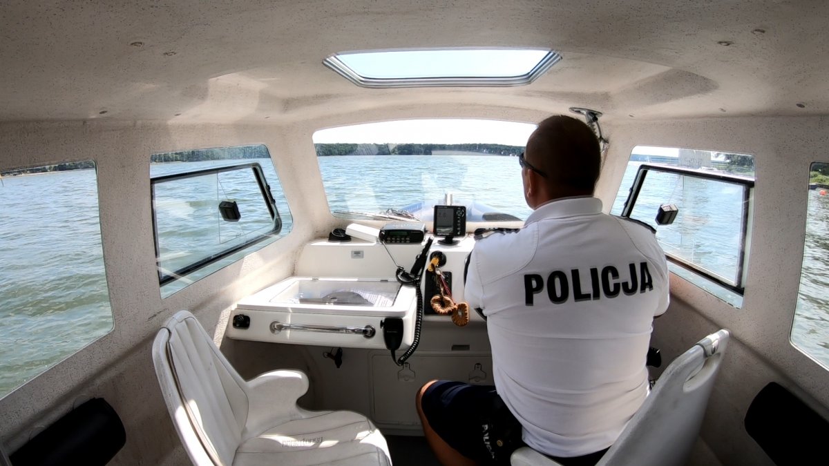 Kokpit łodzi policyjnej z policjantem za sterami.