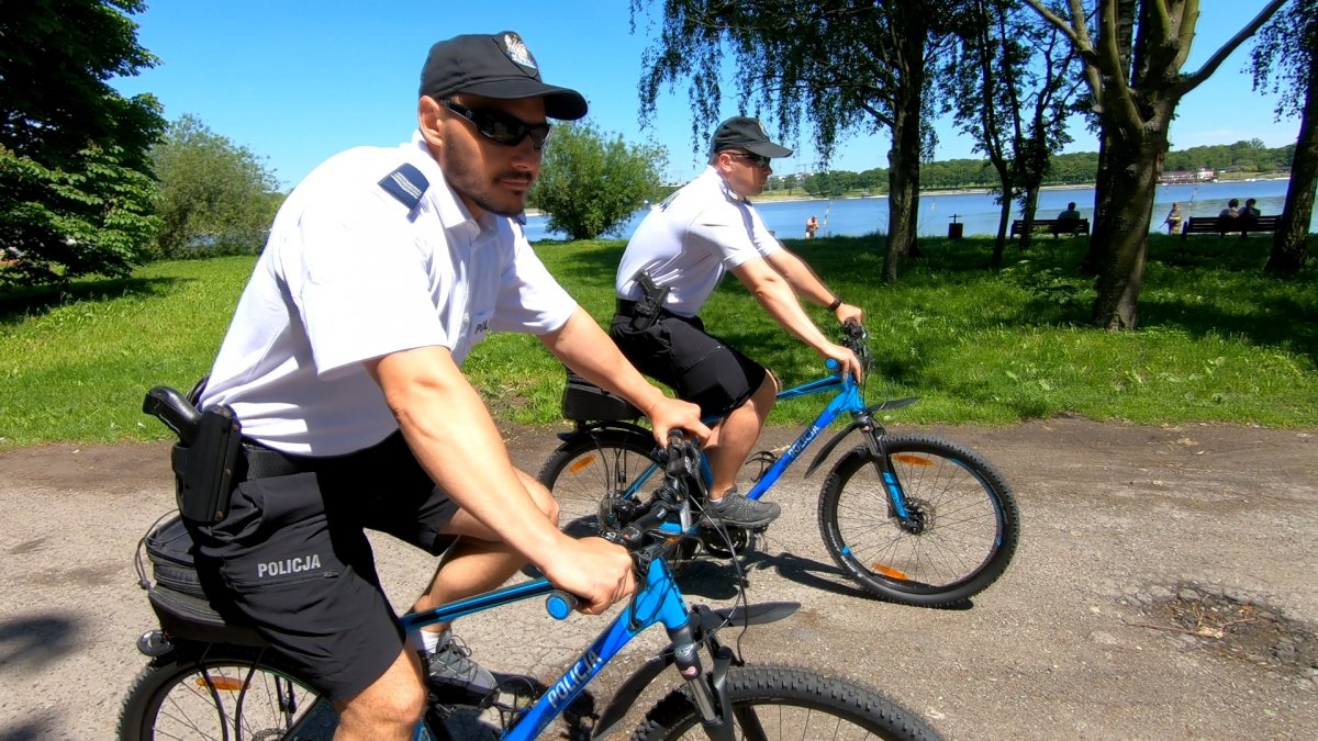 Dwóch policjantów na rowerach jedzie scieżką.
