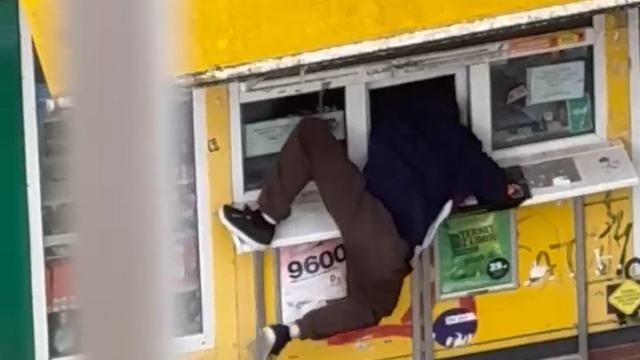Stop klatka z filmu na którym widać jak mężczyzna włamuje się do kiosku.