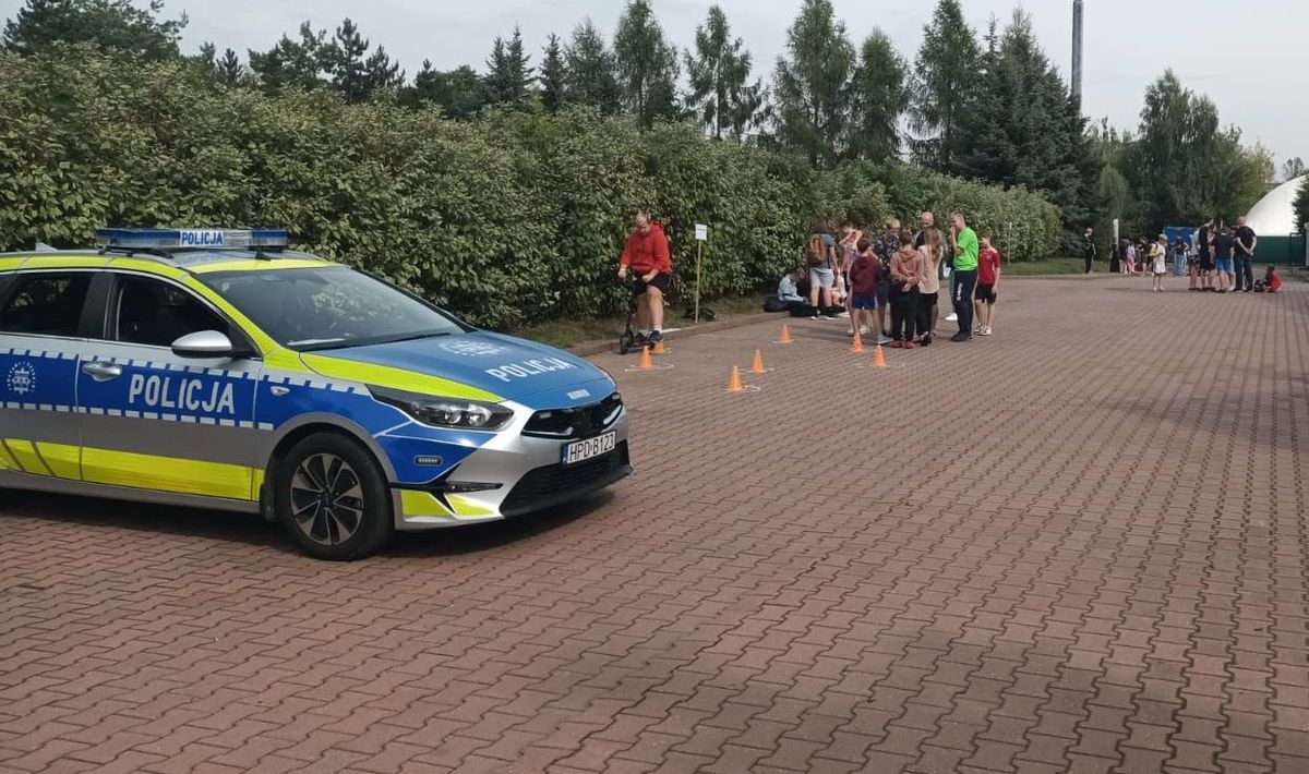 uczestnicy festynu na torze przeszkód, w tle widać radiowóz