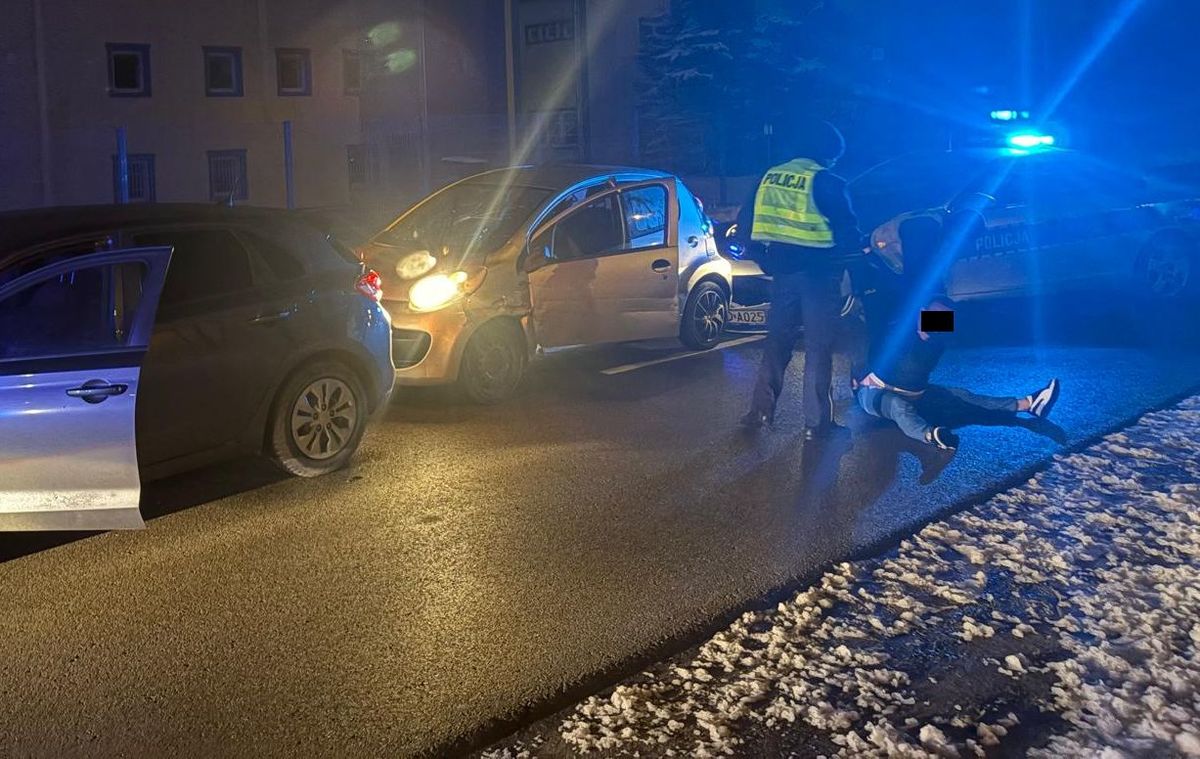 policjanci na ulicy z zatrzymanym mężczyzną, w tle widać dwa radiowozy i auto, którym uciekał
