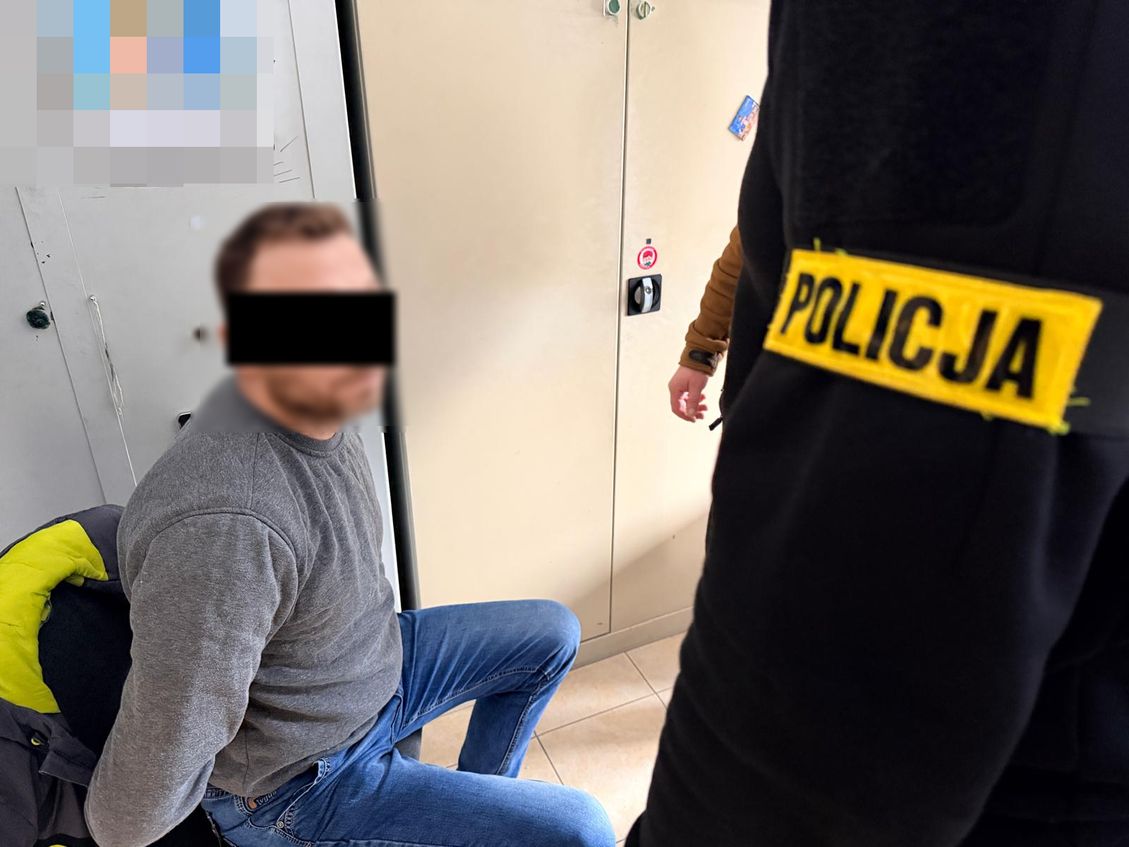 Zatrzymany mężczyzna z założonymi kajdankami na ręce trzymane z tyłu.