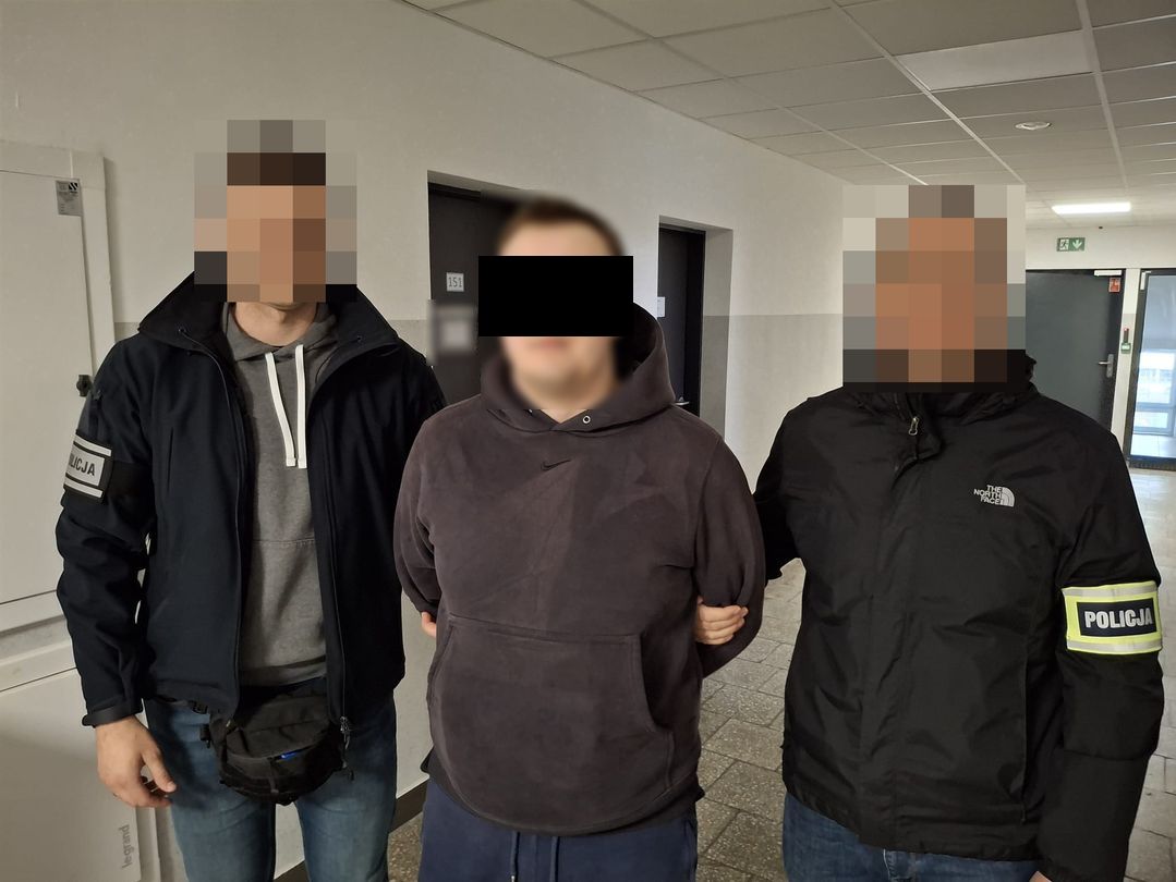 Policjanci prowadzą zatrzymanego mężczyznę.