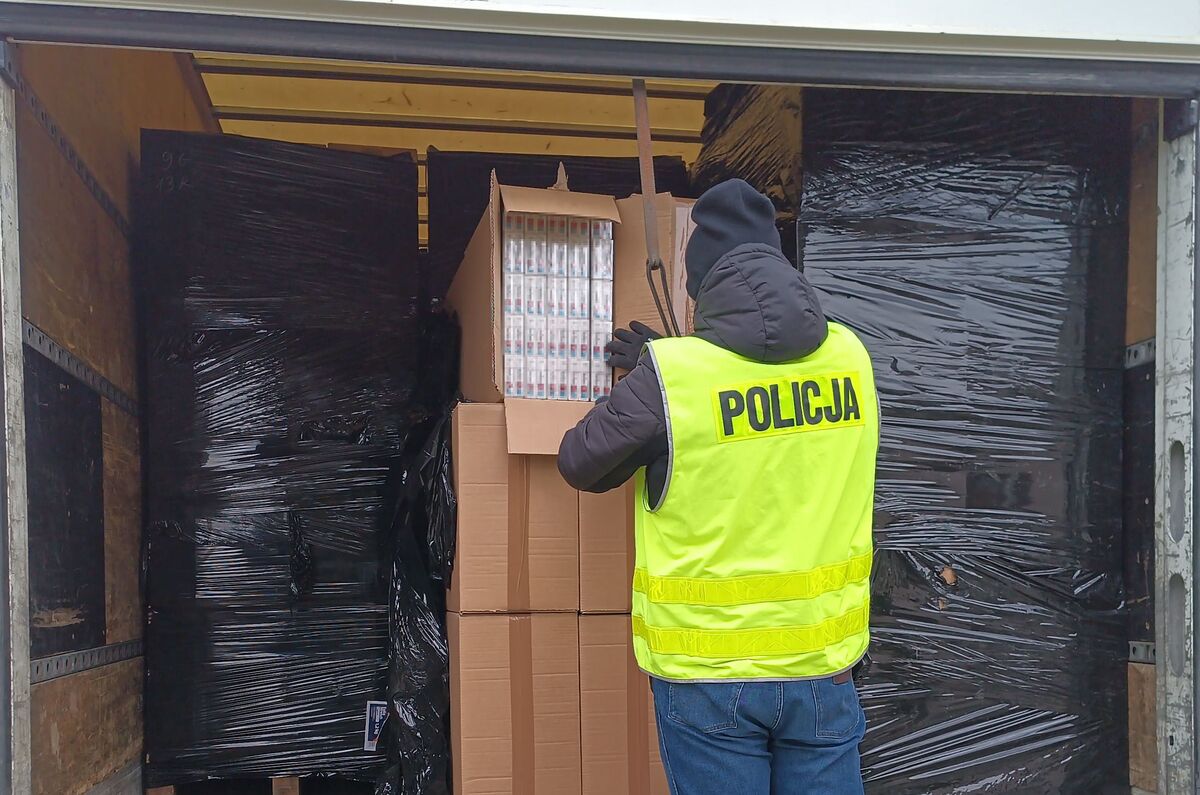 Policjant sprawdza kartony na pace ciężarówki.