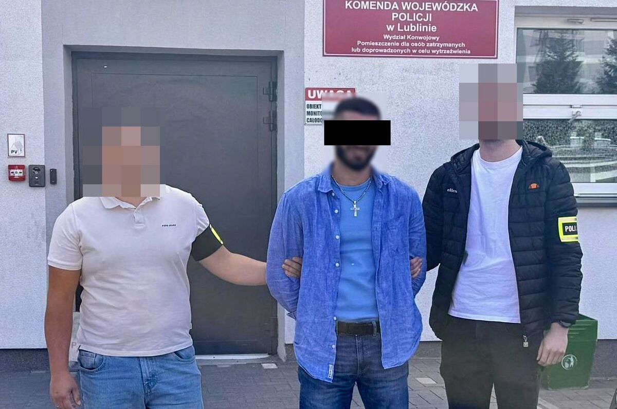 Policjanci prowadzą zatrzymanego mężczyznę.