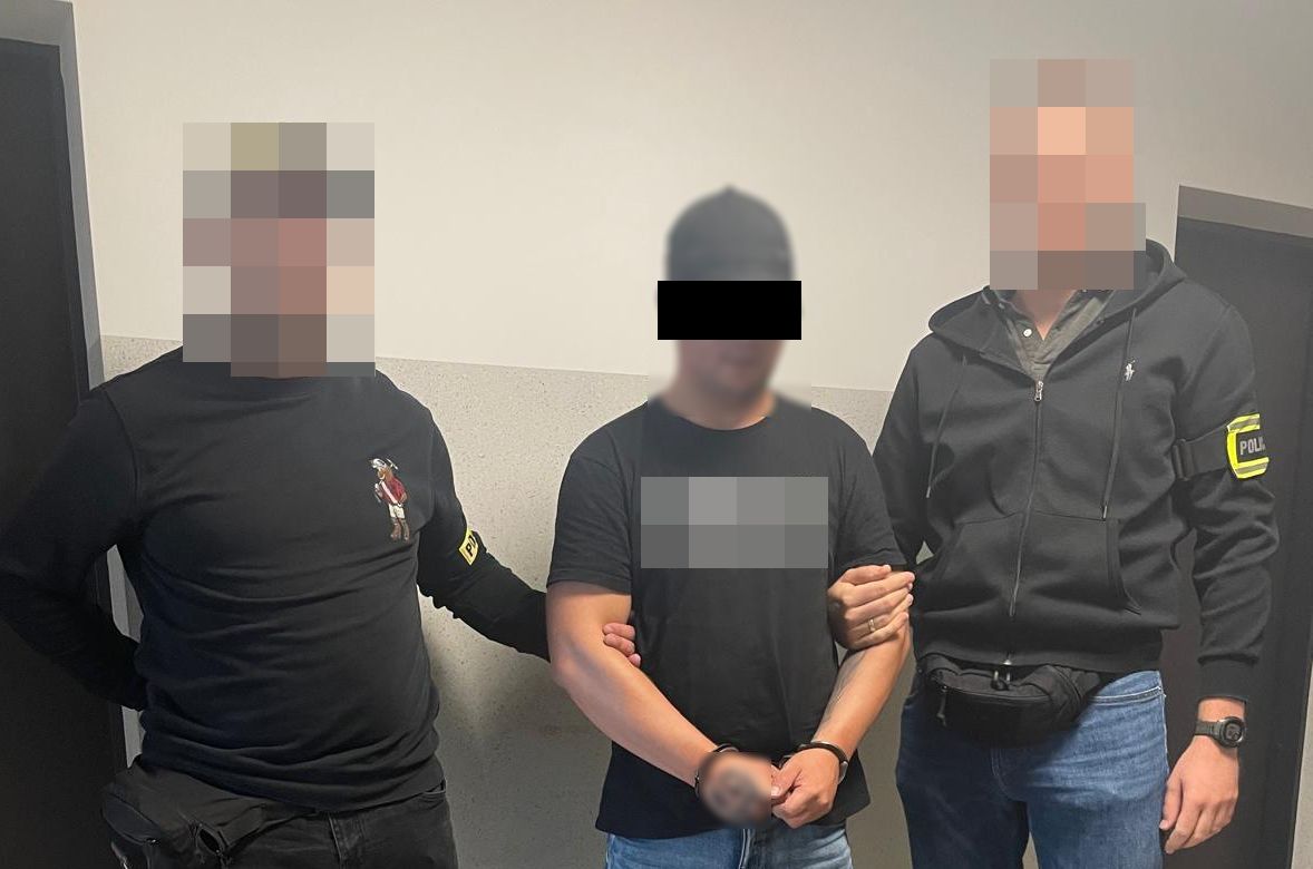 Policjanci prowadzą zatrzymanego mężczyznę.