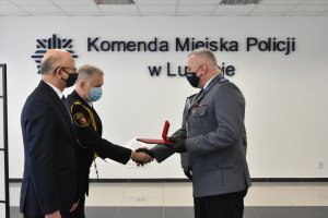 komendant odbiera gratulacje i medal od prezydenta miasta i szefa straży miejskiej