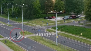 Ujęcie z drona na którym widać mężczyznę który przejeżdża przez przejście dla pieszych na hulajnodze.