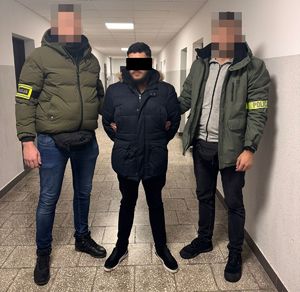 policjanci prowadzą zatrzymanego mężczyznę