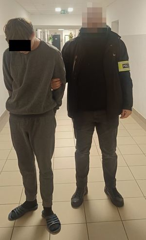 policjant podczas doprowadzenia zatrzymanego