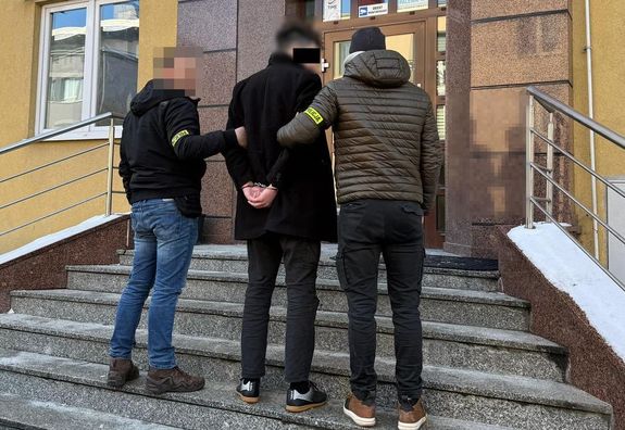 Policjanci prowadzą zatrzymanego mężczyznę do prokuratury.