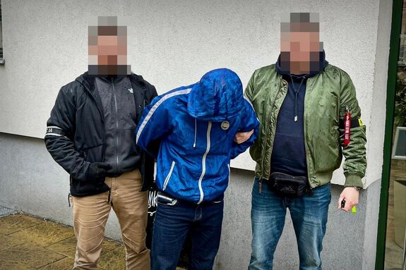 Policjanci prowadzą zatrzymanego mężczyznę.