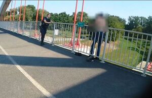 policjantka na moście rozmawia z mężczyzną stojącym za barierką