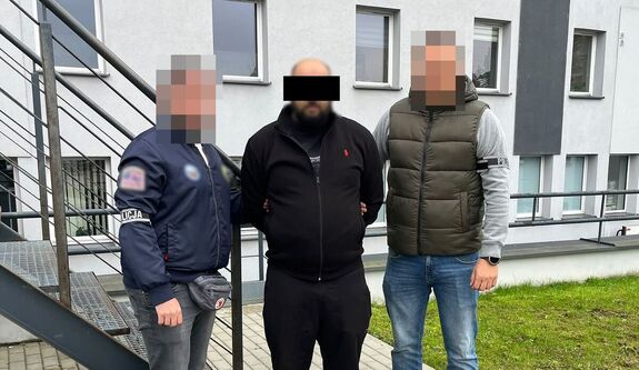 Policjanci prowadzą zatrzymanego mężczyznę.