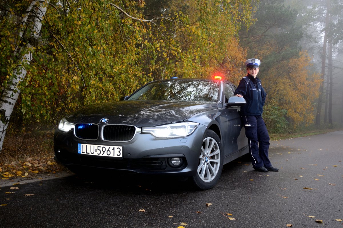 Policjantka oparta o radiowóz nieoznakowany.