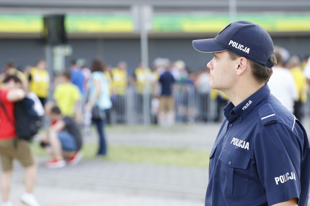 policjant w tle widać kibiców i stadion