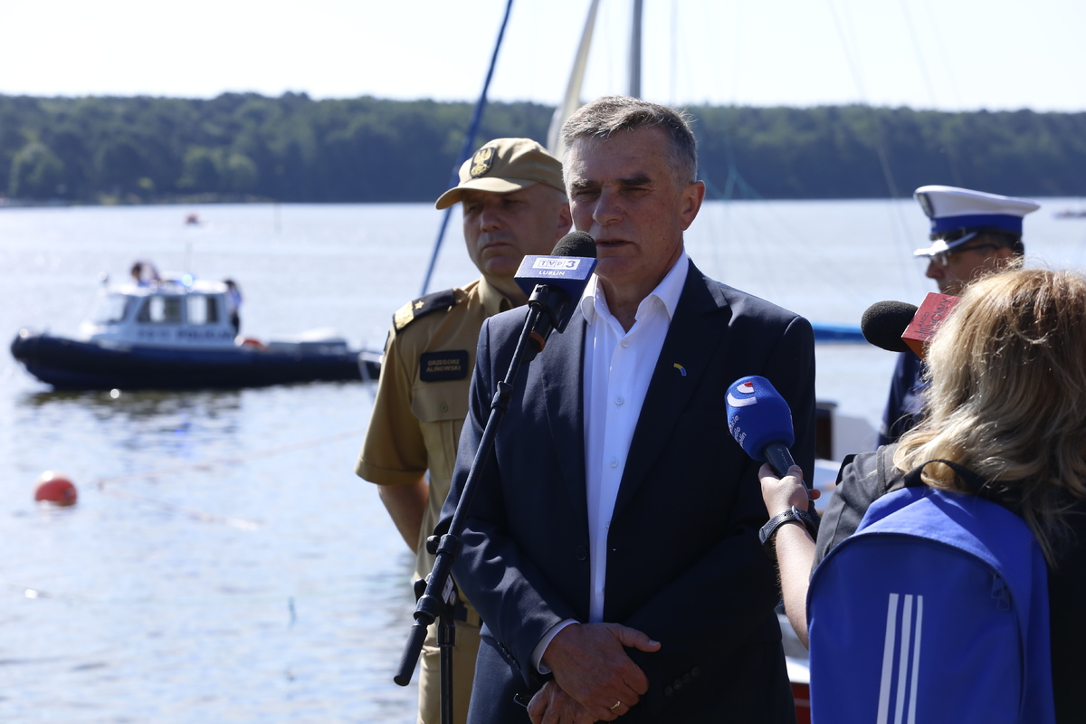 Wojewoda Lubelski Lech Sprawka udziela wywiadu dziennikarzom. W tle Zalew Zemborzycki oraz policyjna łódź.