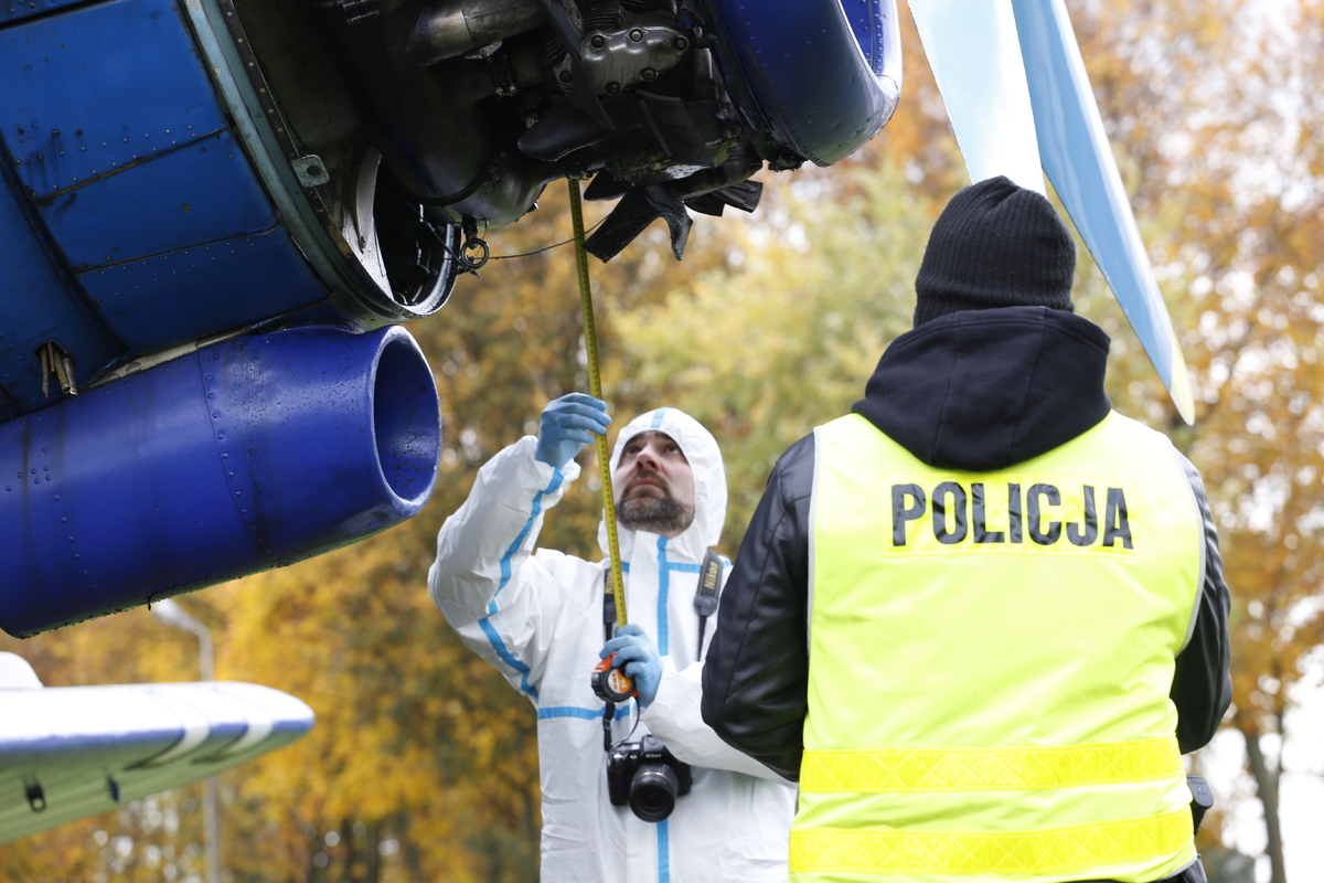 Technicy policyjni zbierają ślady z miejsca wypadku lotniczego.