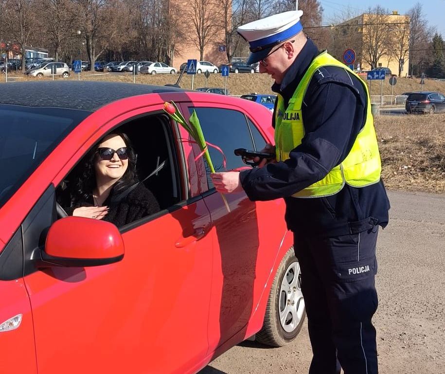 policjant drogówki wręcza kwiat kierującej 