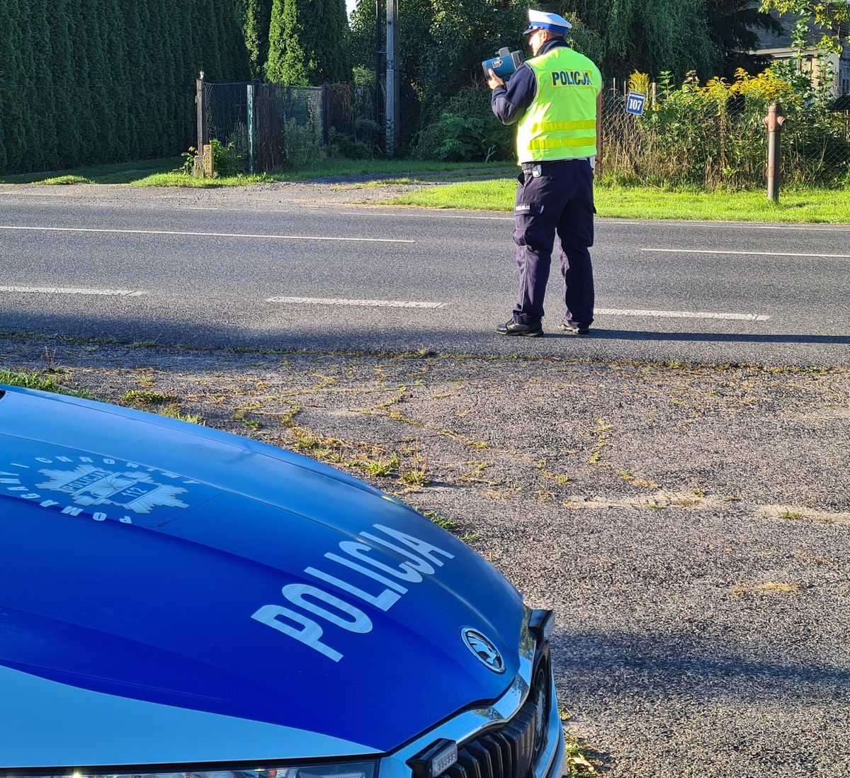 policjant z miernikiem prędkości przy drodze