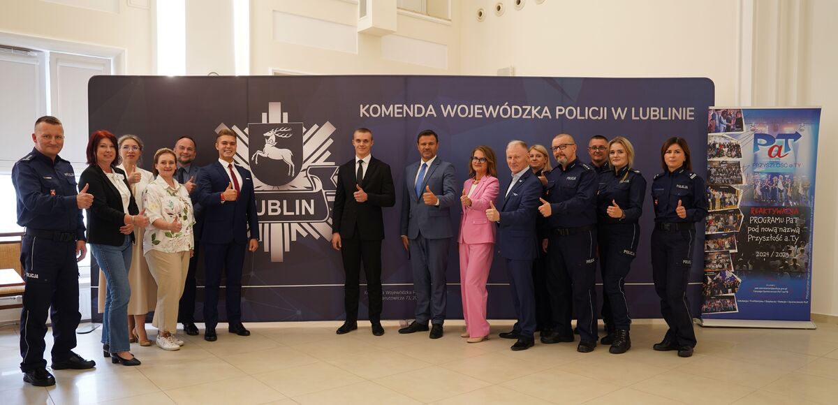 Grupowe zdjęcie uczestników spotkania na tle ścianki z napisem Komenda Wojewódzka Policji w Lublinie