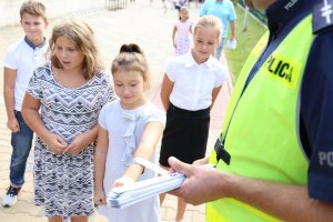 Policjanci dają dzieciom odblaski.