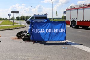 motocykl leżący na skrzyżowaniu, parawan z napisem policja, w tle widać radiowóz i wóz strażacki