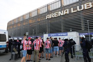 policjanci przed stadionem i kibice w drodze na mecz