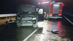 rozbity czarny pojazd, obok pojazd straży pożarnej