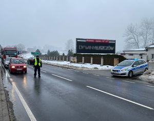 policjant kieruje ruchem na drodze, obok radiowóz