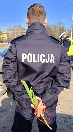 policjant z kwiatami trzymanymi z tyłu