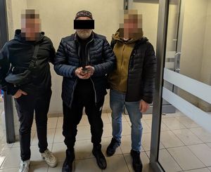 policjanci prowadza zatrzymanego mężczyznę
