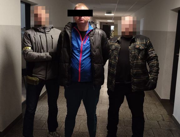 dwaj policjanci prowadzą po korytarzu zatrzymanego 37-latka